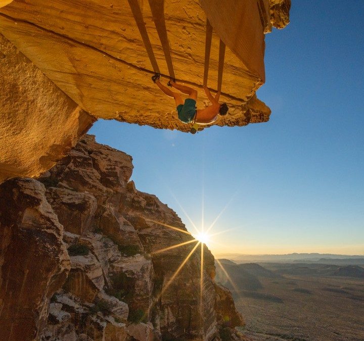 Alex Honnold climbs a mountain edge as the sun sets in The Soloist VR.