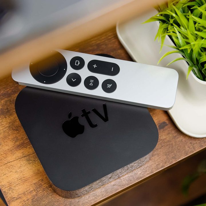 An Apple TV 4K set-top box and remote control sit on a media stand.