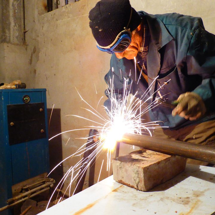 Sparks fly as a man uses an arc welder on a pipe.