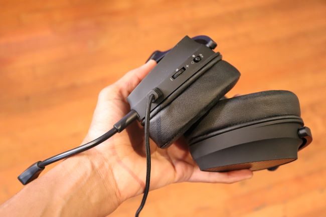 The Asus ROG Delta S Animate held in a hand and viewed from the bottom, showing the volume wheel, LED toggle button, and microphone.