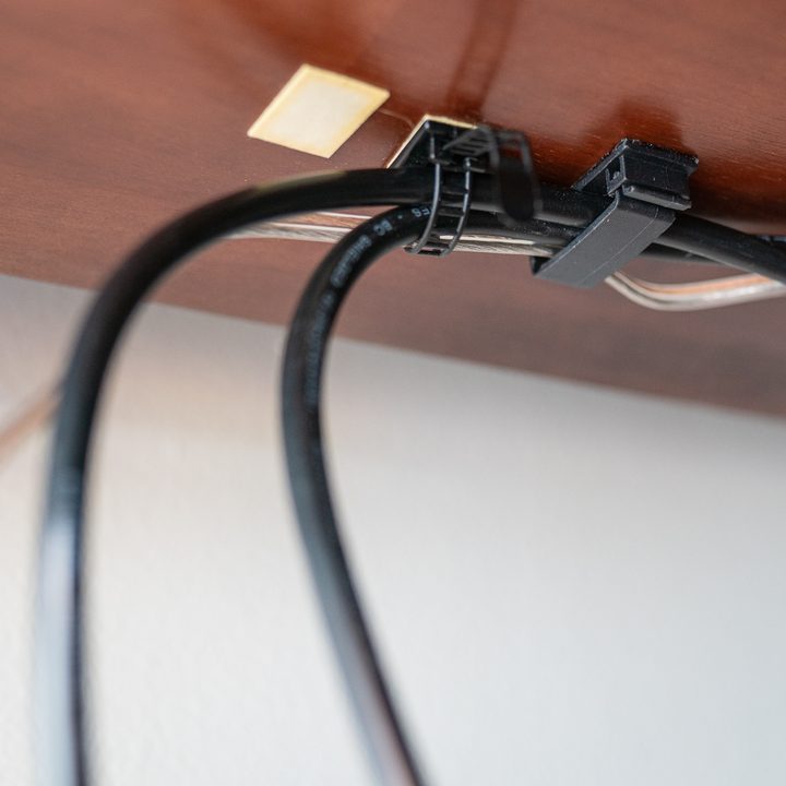 Cables attached with clips under a desk.