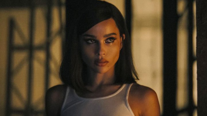 Selina wears a white tank top and looks over at someone in The Batman.