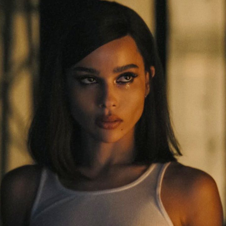 Selina wears a white tank top and looks over at someone in The Batman.