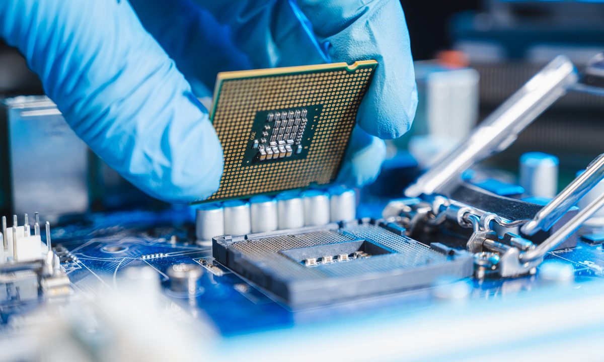 A technician placing a CPU into a motherboard socket for a PC.