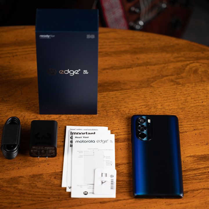 Motorola Edge+ (2022) with included accessories and packaging on a wood table.