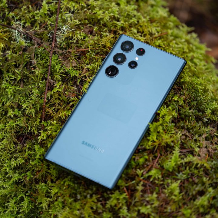 The Samsung Galaxy S22 Ultra resting on greenery in an outdoor setting.