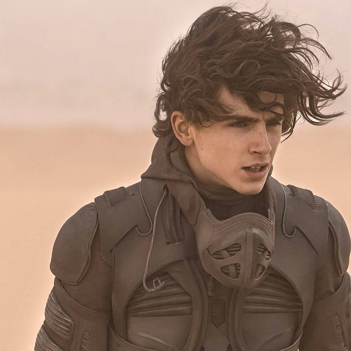 Timothy Chalamet walking in the desert with his hair flying in a scene from Dune.