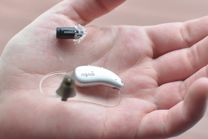 Eargo 6 seen beside a traditional hear aid.