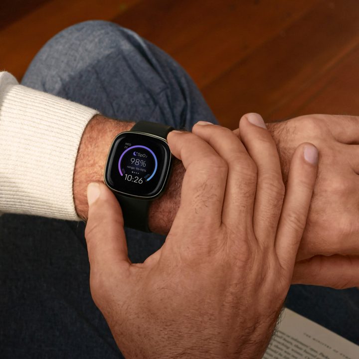 A carbon colored Fitbit Sense is worn on a mans wrist.