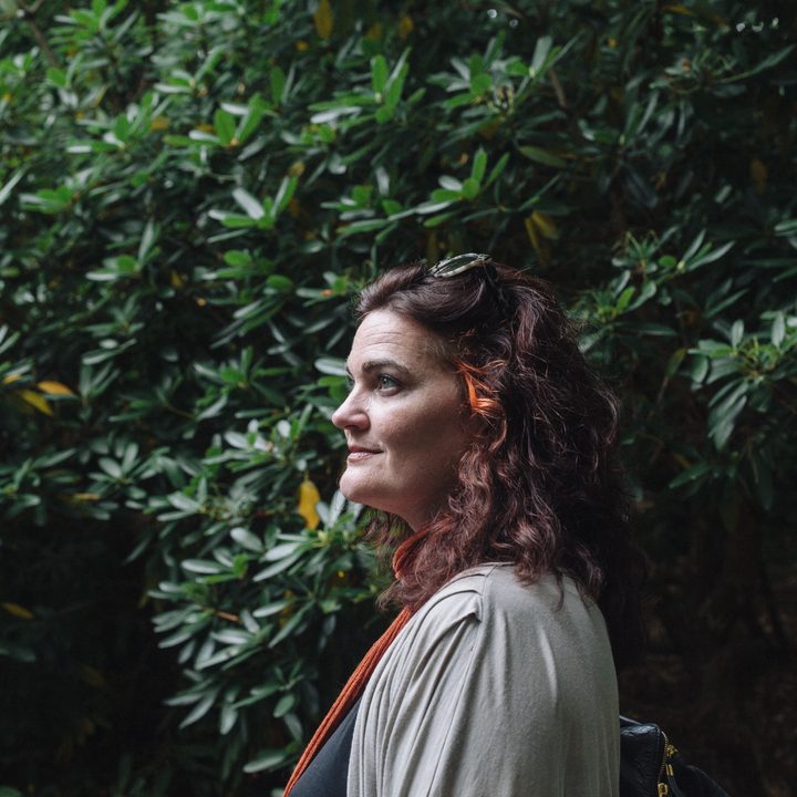 Louisa Heinrich, a UX pioneer, stands in front of some greenery.