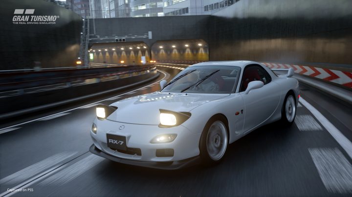 A Mazda Rx 7 drifts in the rain on a Tokyo Expressway in Gran Turismo 7.