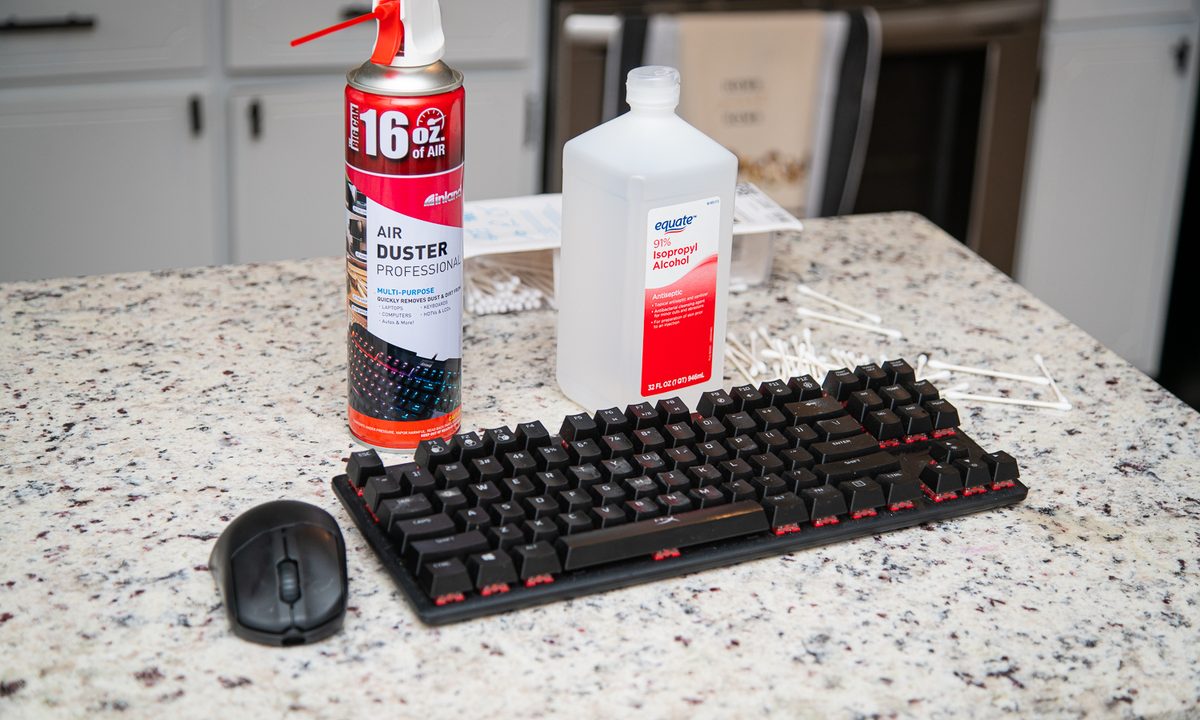 A keyboard, mouse, and cleaning supplies sitting on a counter.