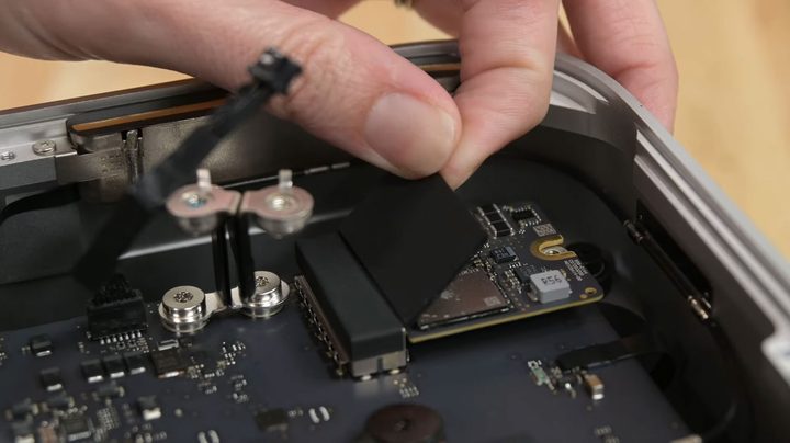 An iFixit engineer tearing down Apple's Mac Studio by removing an SSD drive.