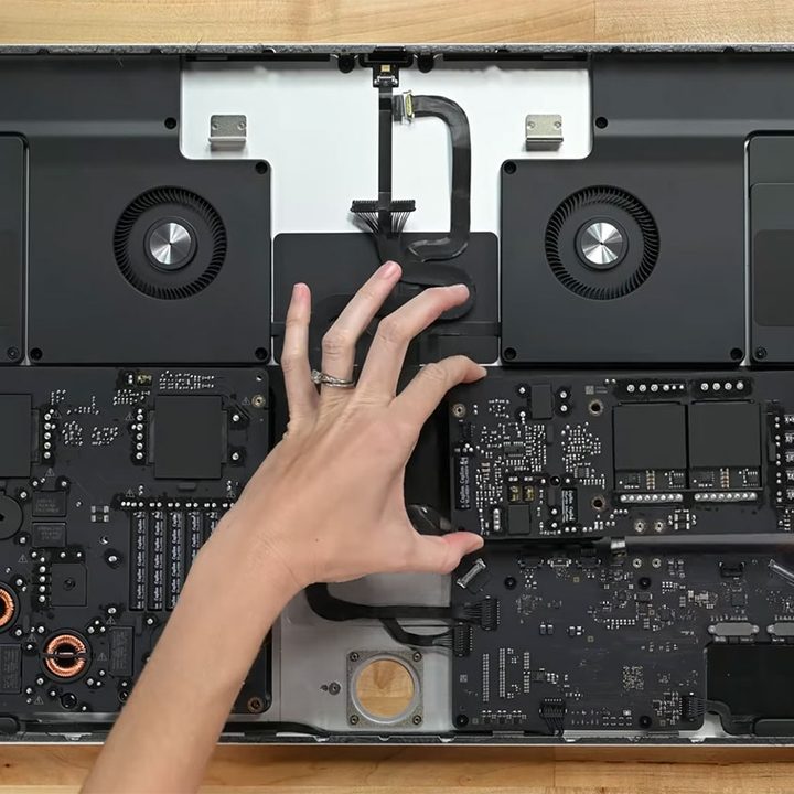 iFixit's Apple Studio Dislpay teardown, showing the internals of the monitor with the power supply being removed.