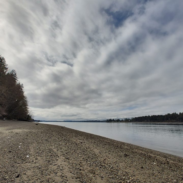 Rocky beach under a partly cloudy sky next to a calm sea.