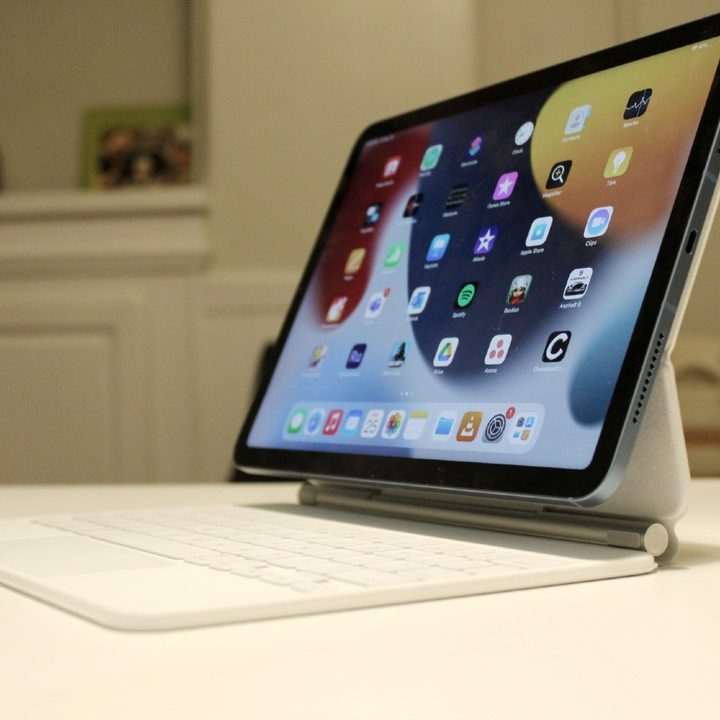 Someone holding an iPad Air against a wooden floor.