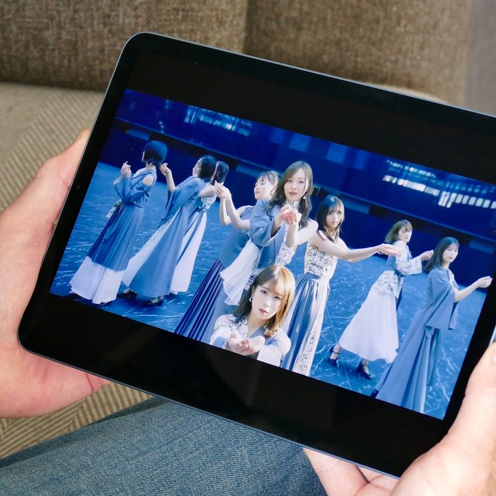 A video plays on the iPad Air 5 being held in a pair of hands.