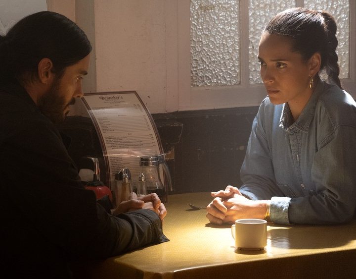 Jared Leto and Adria Arjona sit at a table in a scene from Morbius.