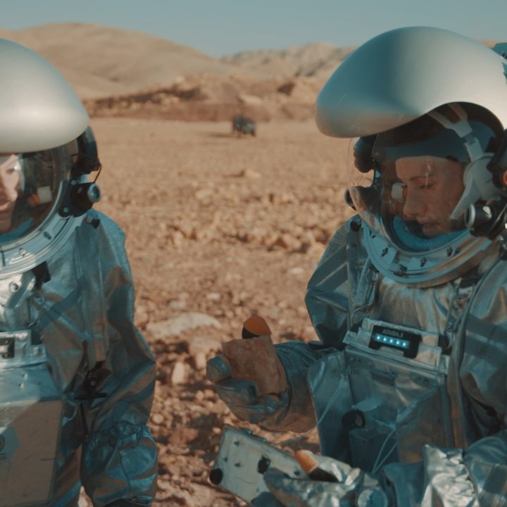 A pair of scientists in astronaut suits simulate Mars exploration in the desert.