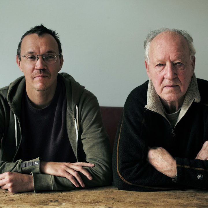 Rudolph Herzog and his father, Werner Herzog, sit at a table, facing the camera.