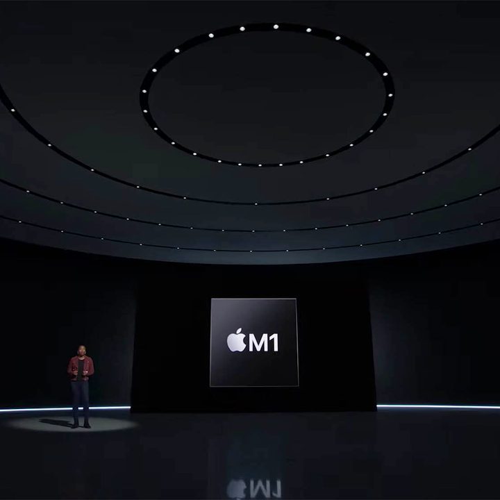 A man stand on the stage at Apple's Peek Performance event, with an M1 logo behind him.