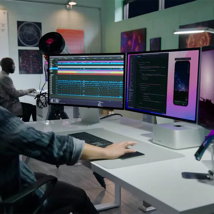 A person works at a station equipped with the all new Mac Studio and Studio Display.