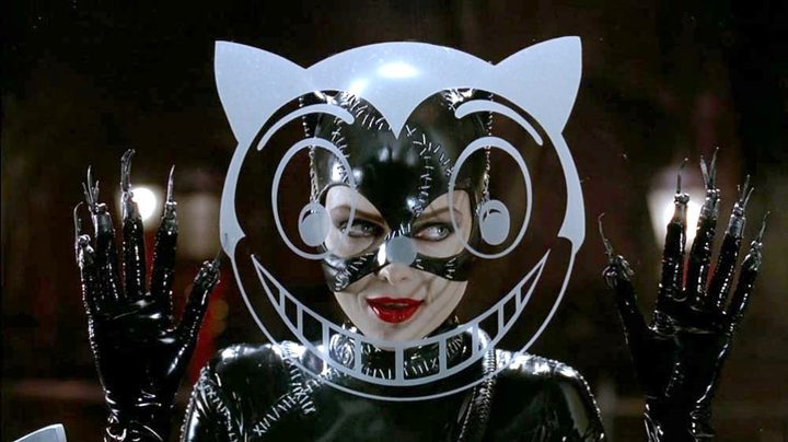 A smiling Catwoman peers through a glass window in Batman Returns.