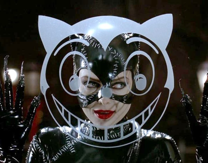 A smiling Catwoman peers through a glass window in Batman Returns.