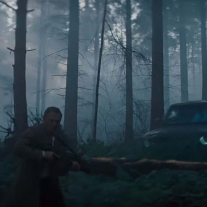 A car flips over James Bond in a forest in a scene from No Time To Die.