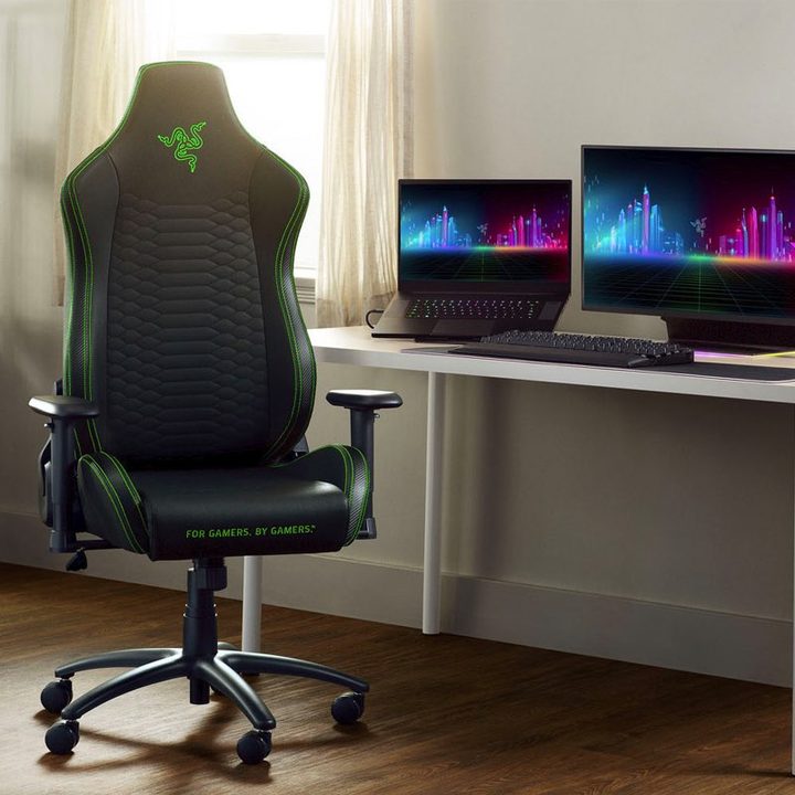 A Razer Iskur X gaming chair sits by a gaming PC and laptop setup.