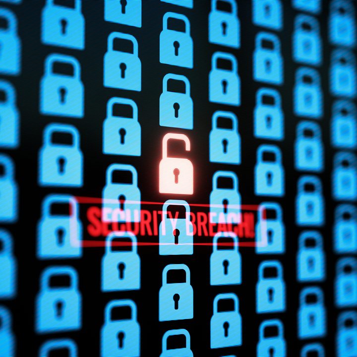 A large monitor displaying a security hacking breach warning.
