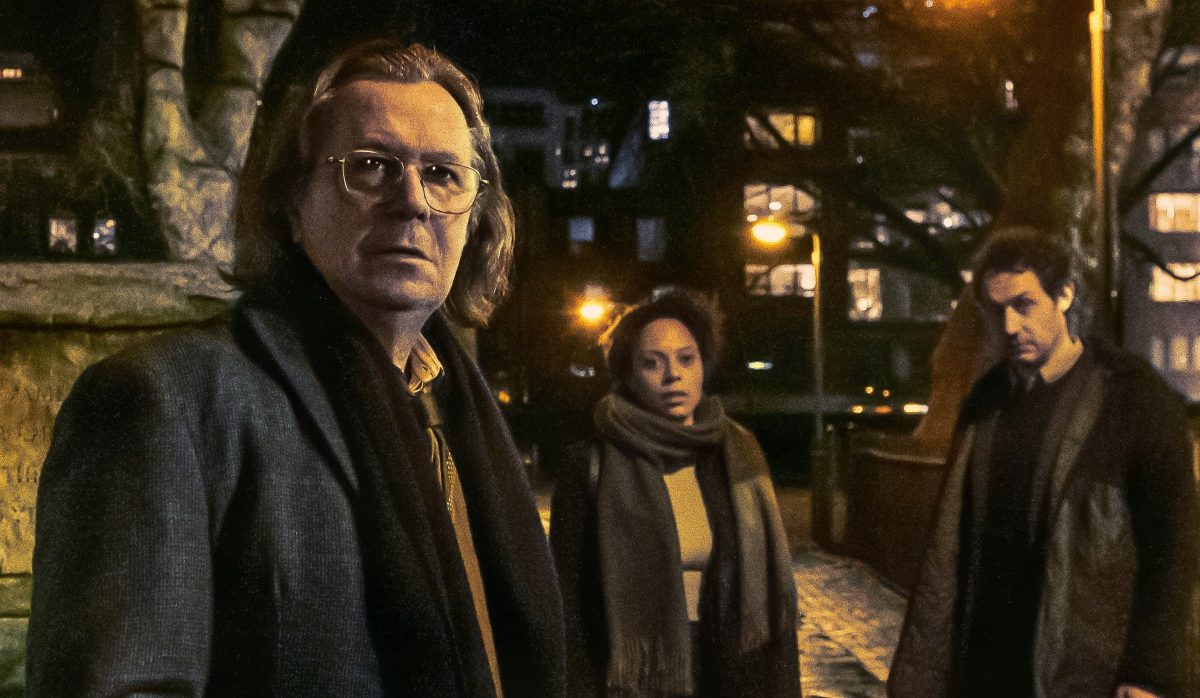 Gary Oldman and the cast of Slow Horses stand on a sidewalk at night.