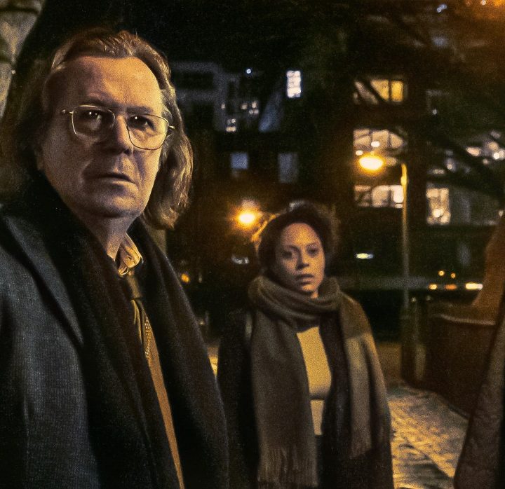 Gary Oldman and the cast of Slow Horses stand on a sidewalk at night.