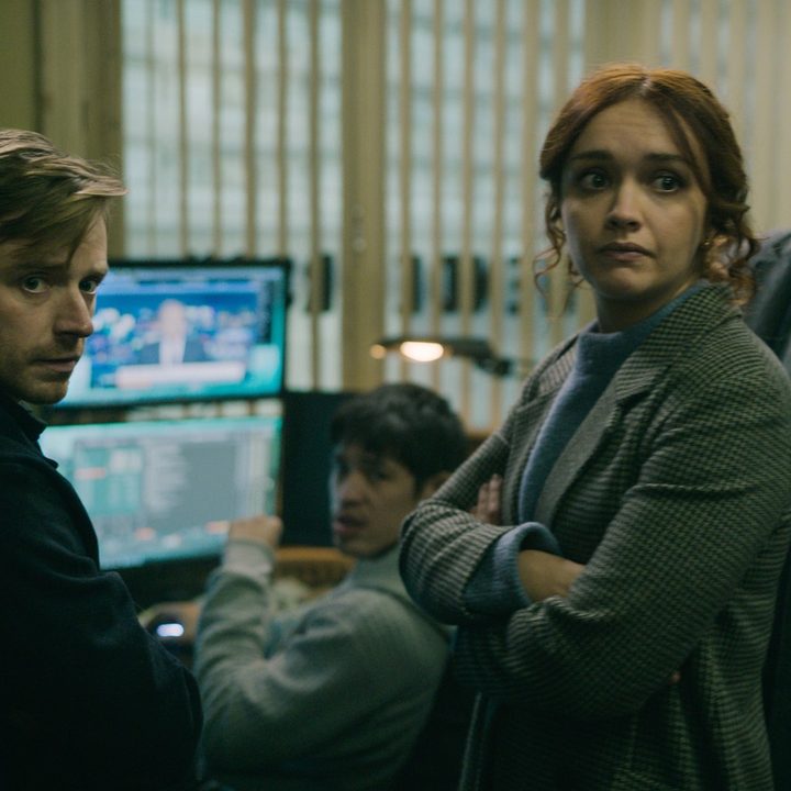 The cast of Slow Horses gathers around a set of computers in a scene from the Apple TV+ series.
