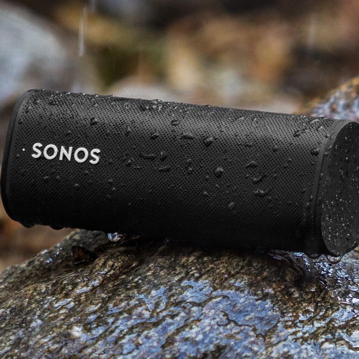 Sonos Roam SL in black on a rainy rock outdoors.