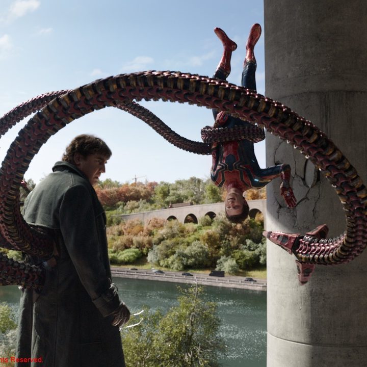 Doctor Octopus holds Peter Parker upside down in a scene from Spider-Man: No Way Home.