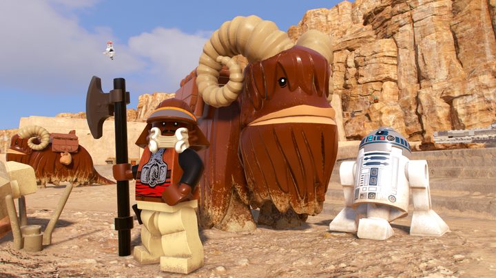 Lando and R2D2 stand by a Bantha in Lego Star Wars: The Skywalker Saga.