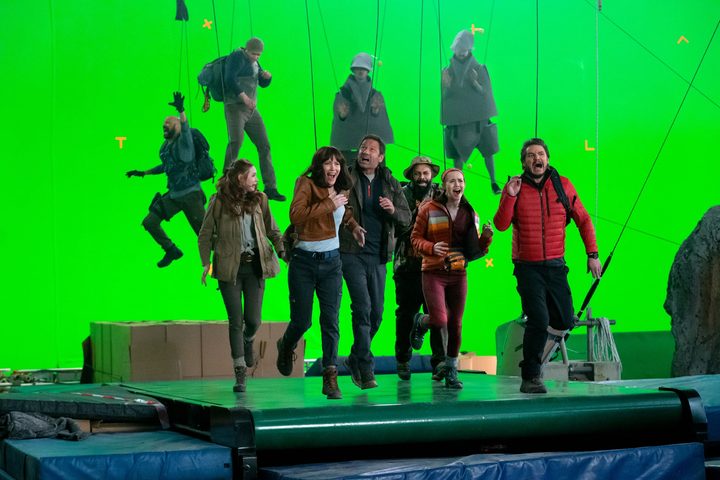 The cast of The Bubble pretends to run against a green-screen backdrop in a scene from the film.