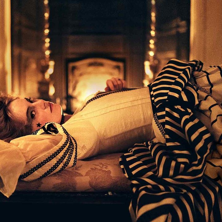 Emma Stone lays down in front of a fireplace in The Favourite.