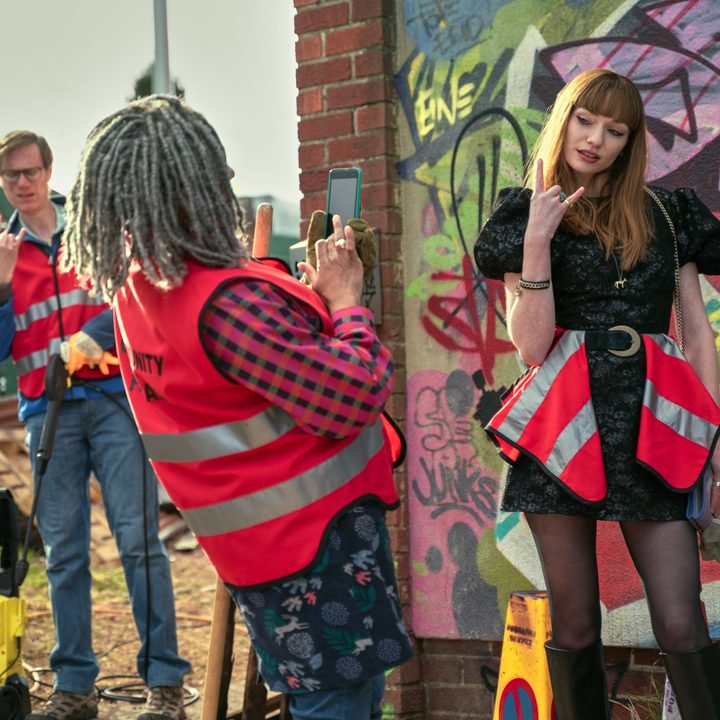 A woman takes a picture of a fellow community service team member in The Outlaws.