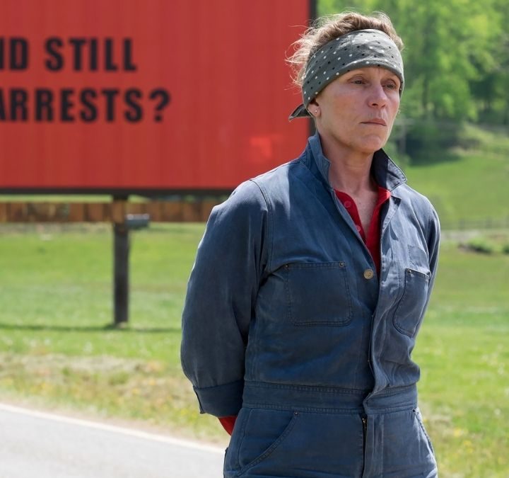 Mildred standing in front of a billboard in Three Billboards Outside Ebbing, Missouri.