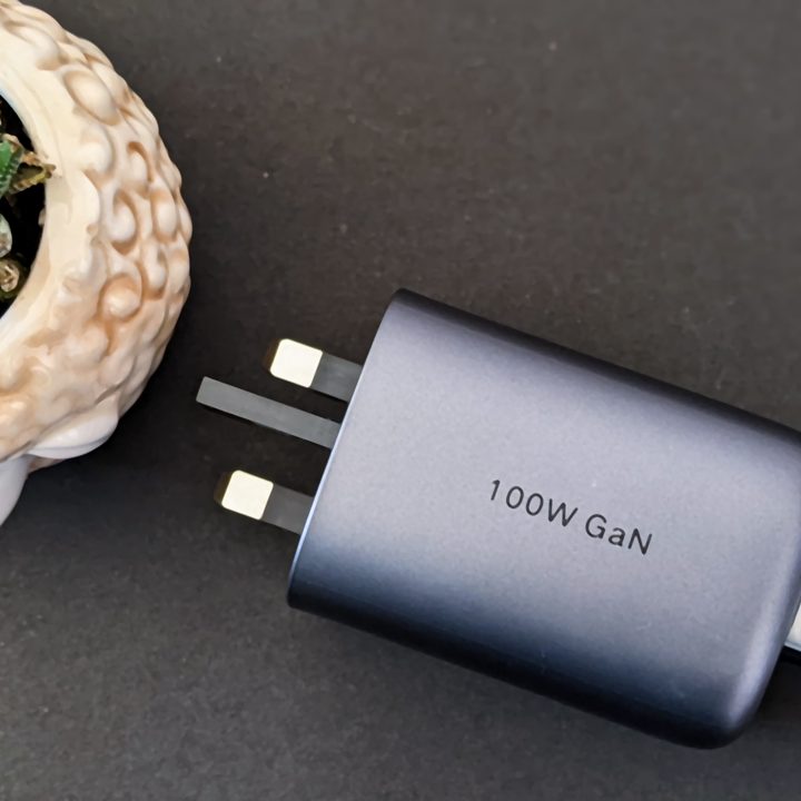 The Ugreen 100-watt GaN gallium nitride charger next to a succulent in a lamb-shaped pot on a black background.