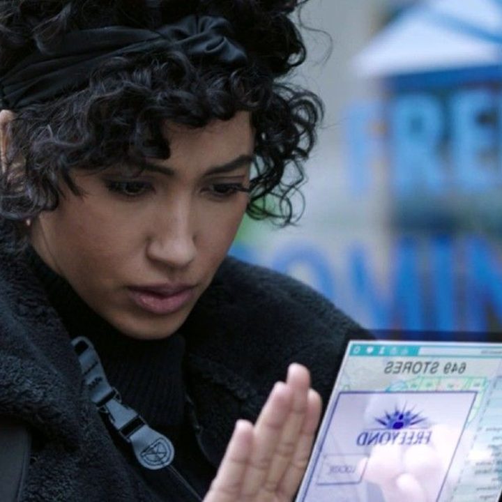 Nora looks at the computer in her hand in a scene from Upload on Amazon Prime.