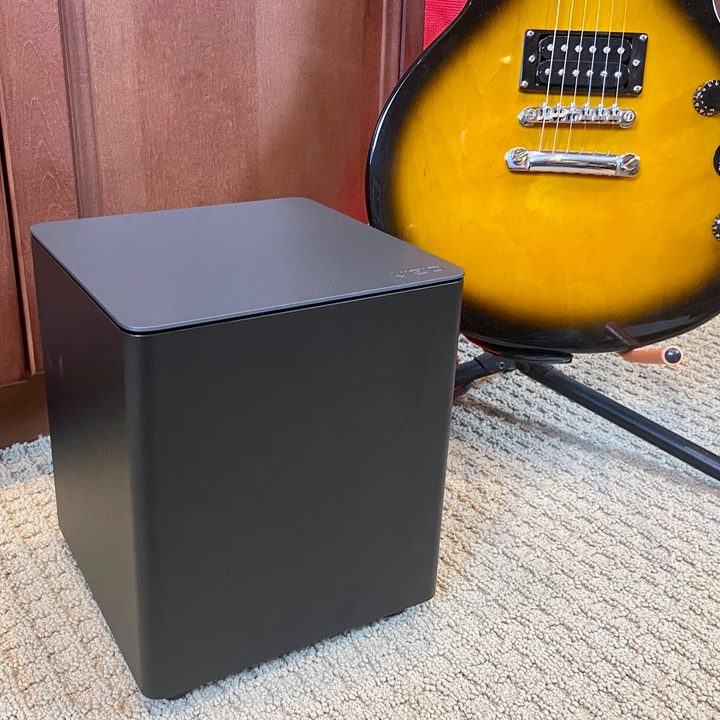 Vizio M-Series 2.1 soundbar's wireless subwoofer next to a guitar.