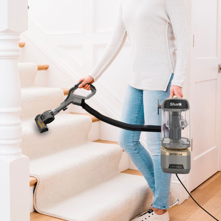 Woman vacuuming stairs with Shark Rotator Lift-Away ADV DuoClean Engage Upright Vacuum.