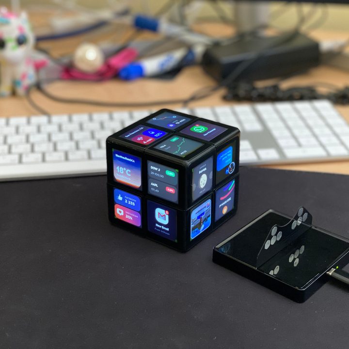 The Wowcube displays several apps while sitting on a desk in front of a keyboard.
