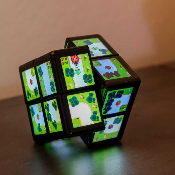 A Wowcube displays a game with a ladybug as it sits ion a table.