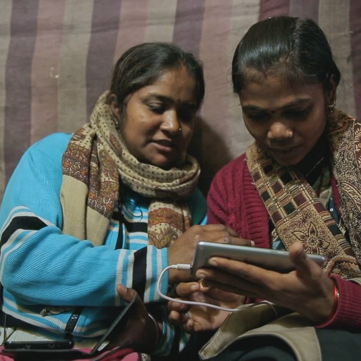Two women discuss how to use an iPhone in a scene from Writing With Fire.