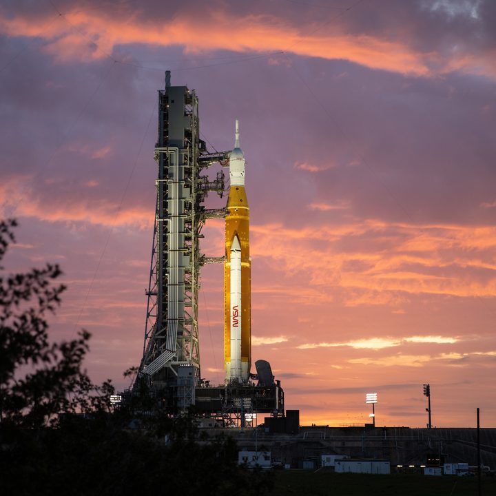 Space Launch System ready for wet dress rehearsal, a sunrise in the background.
