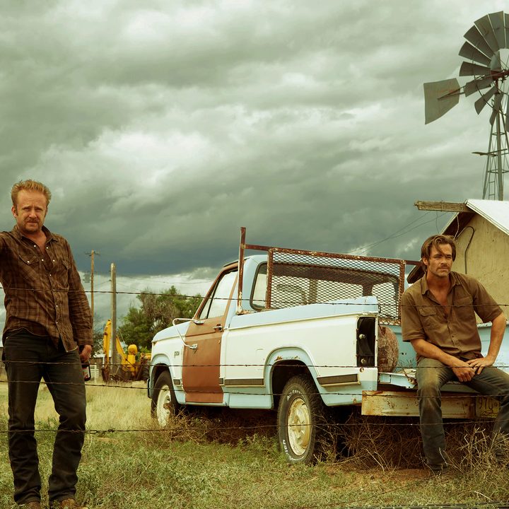 Ben Foster stands near Chris Pine in Hell or High Water.